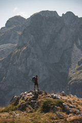 Person standing in a verdant field with mountains in the background.