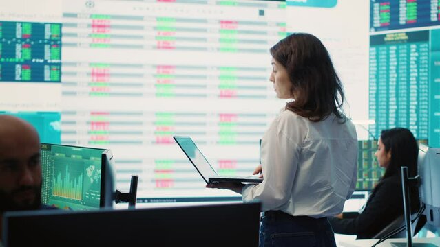 Member of the advisory board examines potential business expansion, supervisor look into data visualizations on a big screen in the office. Seeks to boost affordable earnings. Camera A.