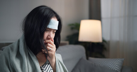 Portrait of Unwell young woman have a high fever feel chills and chronic cough ,wrapped in blanket...