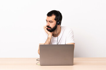 Telemarketer caucasian man working with a headset and with laptop having doubts.