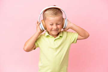 Little Russian boy isolated on pink background listening music