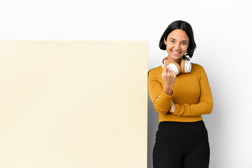 Young woman listening music with a big empty placard over isolated background doing coming gesture