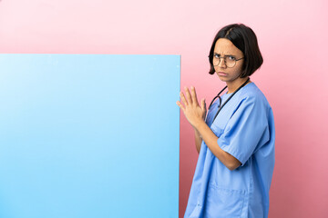 Young mixed race surgeon woman with a big banner over isolated background scheming something