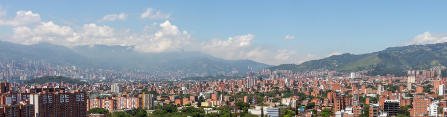 Beautiful panorama (cityscape) of Medellin, Medellín, on a sunny day. The pictures shows condominiums and the Andes Mountains. Antioquia, Colombia. Blue sky, white clouds.