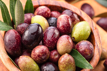 Fresh olives in wooden bowl on the wood background.