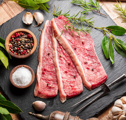 Sliced picanha beef with spices and herbs on a gray stone serving board top view. Traditional Portuguese food.