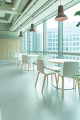 Interior of modern empty office lobby.Open ceiling design.There are floor-to-ceiling Windows and comfortable white chairs and table.