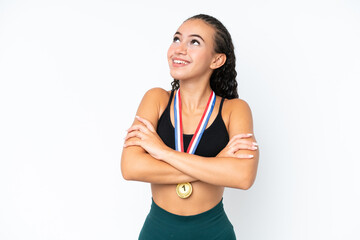 Young sport woman with medals isolated on white background looking up while smiling