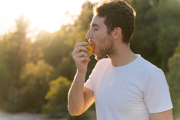 Fototapeta premium Man eating an apple in nature. Healthy lifestyle and nutrition