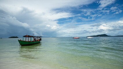 a green boat in the blue water at the beach near an island