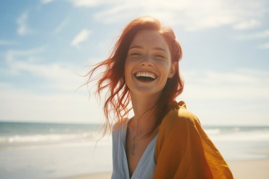 portrait of a redheaded woman, laughing happily on the beach