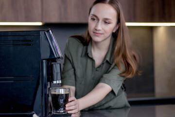 Woman preparing a fresh coffee with a coffee maker machine. Coffee blender and household kitchen...