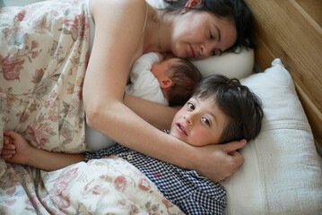 Mother and children sharing an intimate moment in bed, highlighting the bond between mother,...