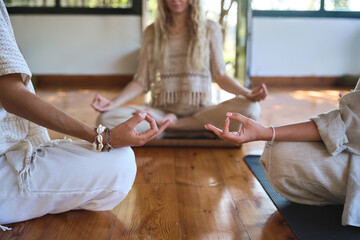 Three diverse women meditating sitting together in yoga poses at body care yoga training. Women...