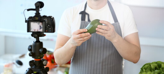 Man Vlogger Showing Ripe Tropical Avocado Fruit. Chef Holding Green Exotic Ingredient. Male Recording Culinary Recipe for Vlog on Camcorder. Healthy Vegetarian Food Partial View Photography.
