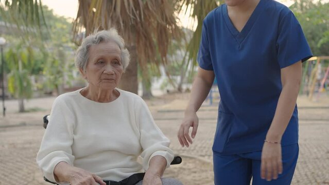 Asian careful caregiver and patient, Nurse gives a pep talk to an elderly female patient in the garden in the evening. Health insurance.