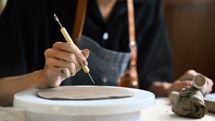 Close-up image of a Young artisan carving and decorating flatting clay with imprint