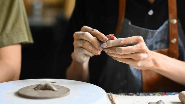 Close-up of an artist's hands sculpting clay, demonstrating precise craftsmanship and creativity. The process of handmade pottery in a studio, showcasing artistry and dedication