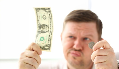 Arms of thoughtful man holding paper and coin currency trying to invent some good solution closeup