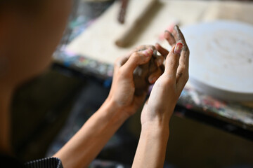 Close-up of an artist's hands shaping clay, emphasizing the tactile and hands-on experience of learning pottery. the creative process and skill development involved in mastering this art form
