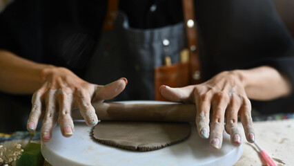 Close-up image of Young Artisan flattening clay on the workbench
