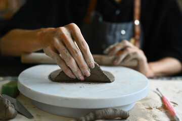 An artist's hand shapes a piece of clay on a pottery wheel, focusing on the intricate details of sculpting. The tactile and creative process of pottery making, emphasizing craftsmanship