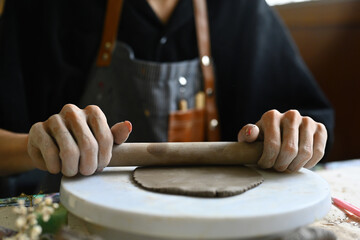 Cropped image of Young sculptor flattening clay by roller, Close-up, Art Workshop, Handicraft,...