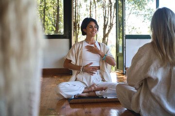 Young happy Hispanic woman yoga coach training group class yoga meditation session sitting in yoga...
