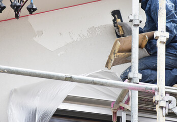 Construction Worker Repairing White Plaster Exterior Wall of a...