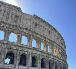Fototapeta premium Exterior walls of Colosseum against the backdrop of a blue sky