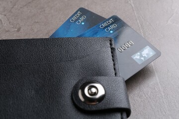 Credit cards in leather wallet on grey textured table, closeup