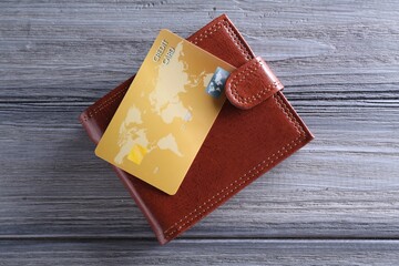 Credit card and leather wallet on grey wooden table, top view