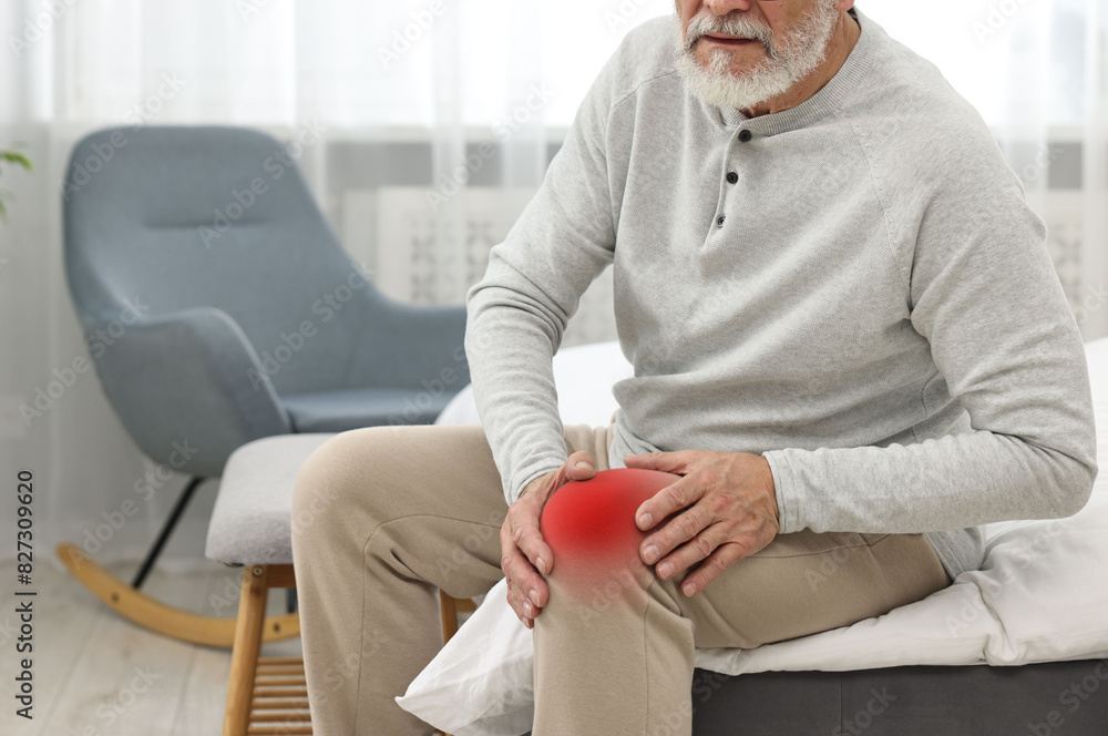 Poster Senior man suffering from pain in knee at home, closeup