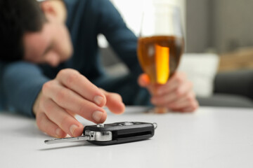 Drunk man reaching for car keys indoors, selective focus. Don't drink and drive concept