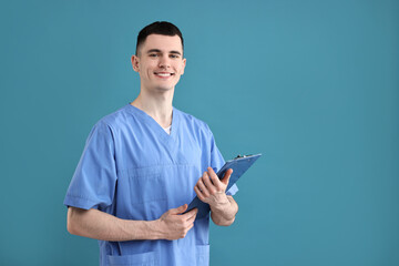 Portrait of smiling medical assistant with clipboard on light blue background. Space for text