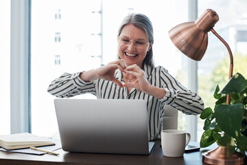Mature woman, video call and heart with laptop at desk for meeting, communication or networking....