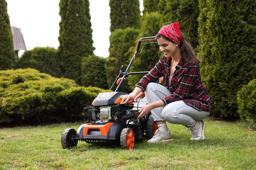 Smiling woman with modern lawn mower in garden