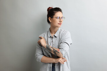 Fototapeta premium Portrait of beautiful tattooed woman on gray background