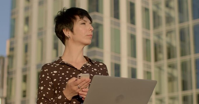 Woman using smartphone against urban backdrop. Technology and modern lifestyle. Sense of connectivity, efficiency, and adaptability humans in the digital era. AI chat bot assistent using.