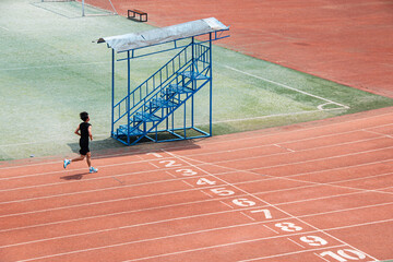 Young student doing long-distance running on a red university track in Wuhan.