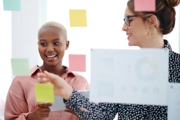 Women, brainstorming or writing ideas on glass wall, paper and sticky note for planning or teamwork...