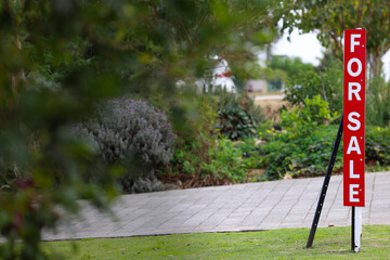 Red, for sale, sign, house in suburban neighborhood, Australia, green garden background. Copy space