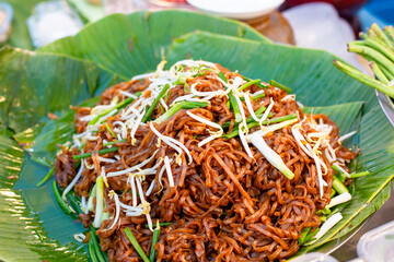 Street food in Asia. Hot noodle dish with sauce on banana leaves. Pad Thai