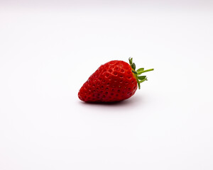 a large strawberry sitting on top of a white surface to show its fruit