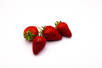 three strawberries sitting on a white surface with the tops slightly down