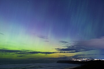 Aurora Australis or southern lights over the city of Dunedin, New Zealand; beautiful purple, pink...