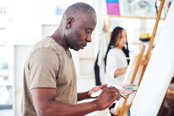 Black man, painting and creative studio or art easel with watercolor palette in class, learning or...