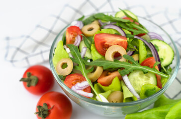 Green vegan salad from fresh vegetables, green leaves, arugula and olives. Close-up. Selective focus.