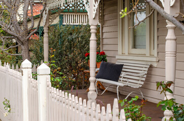 A seat with a cushioned pillow on the front porch decking under the verandah in the front yard...