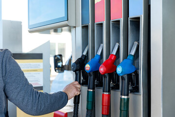 Hand of a man with the gun refueling gasoline or diesel fuel in a white car. Concept of...